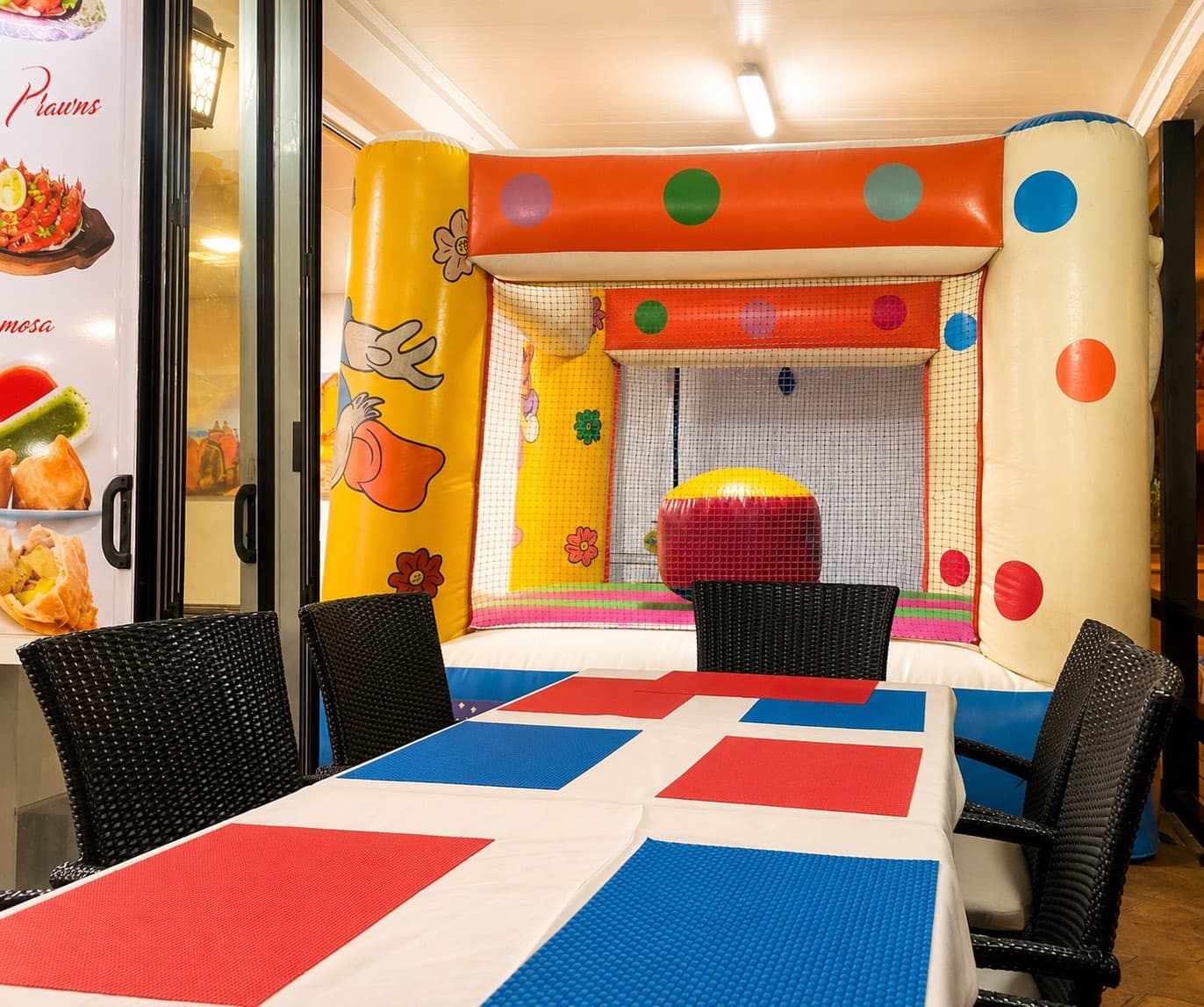 The restaurant's colourful kids' play corner with a soft-play castle beside a set family table